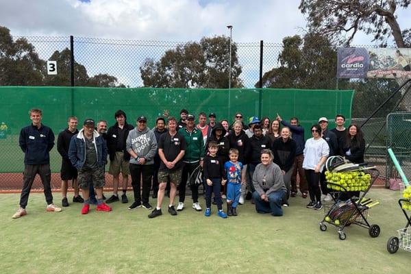 Large group posing on tennis court