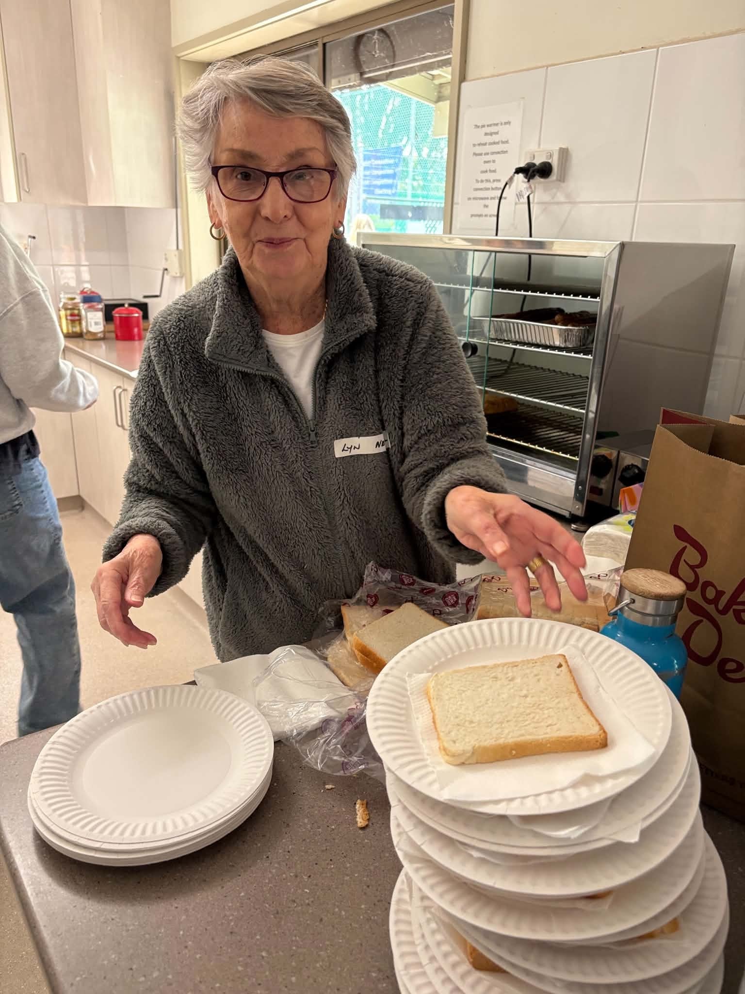 Volunteer preparing bread and plates in the club kitchen